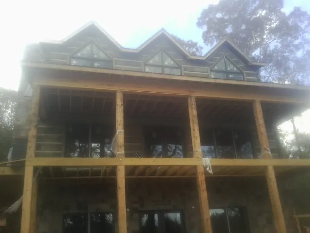 Dormers and porch framing on a large log home under construction — Roof Coating work by our crew in Utica